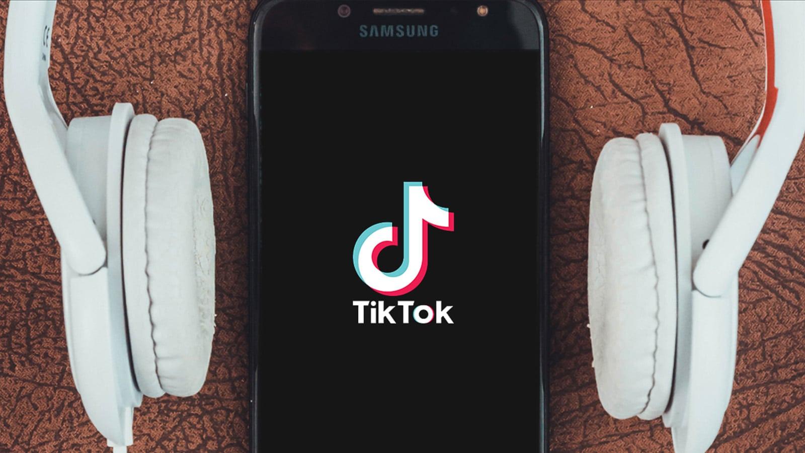 TikTok logo on a phone with white headphones around the outside of the phone