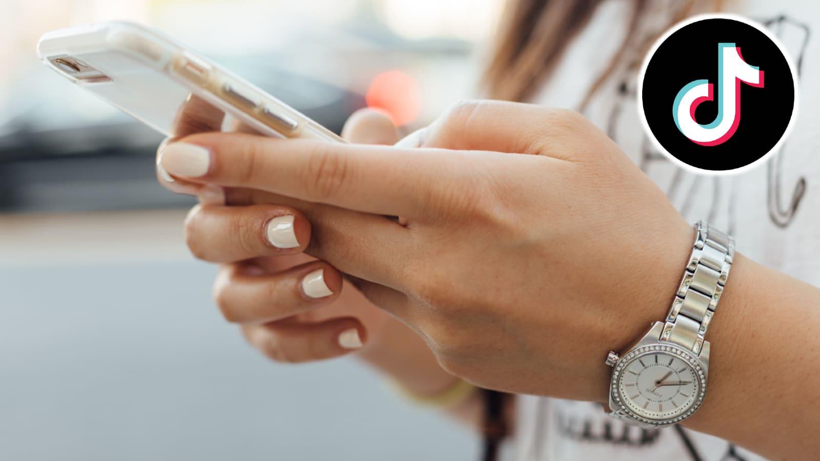 TikTok logo next to hands holding phone