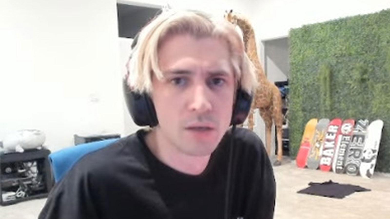 xQc wearing black t-shirt sat at desk staring into camera