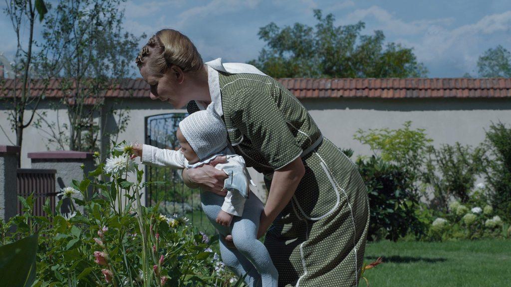 Sandra Hüller as Hedwig Hoss, holding a baby in The Zone of Interest.