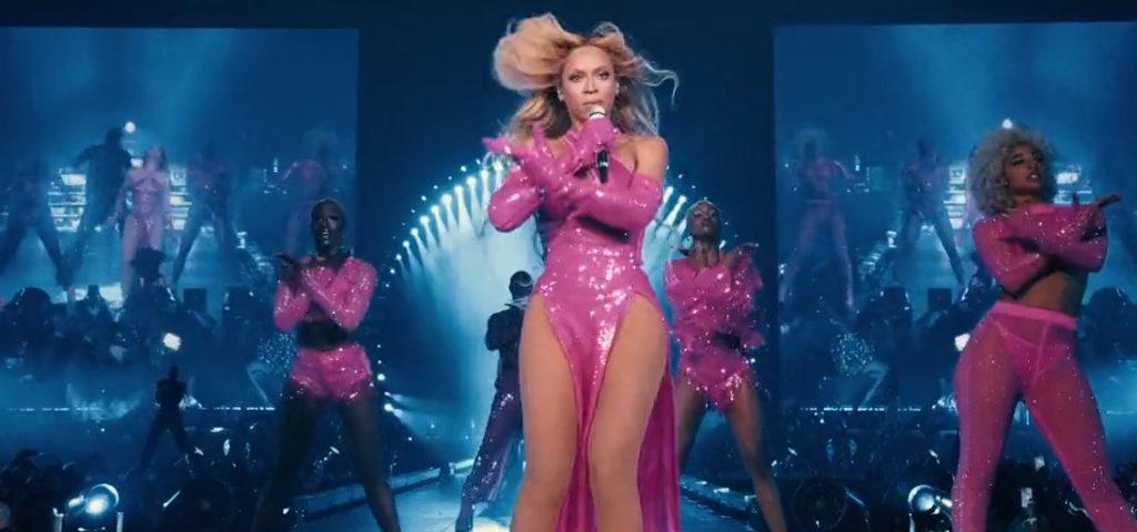 Beyonce performs in a pink dress onstage in a concert.