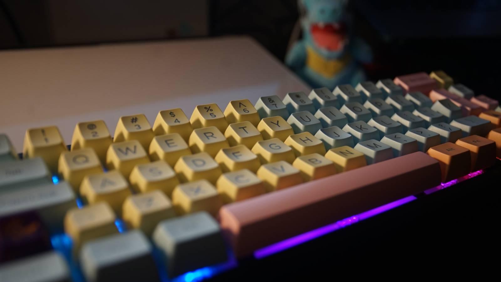 A side view shows a mechanical keyboard on a black desk mat