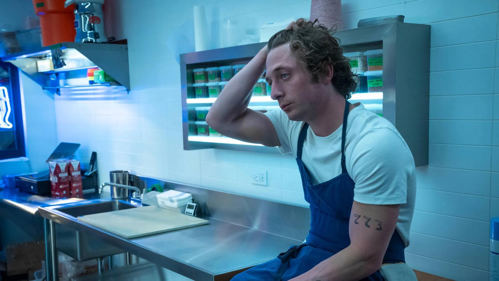 Jeremy Allan White as Carmy in The Bear, sitting on the counter with his hand in his hair