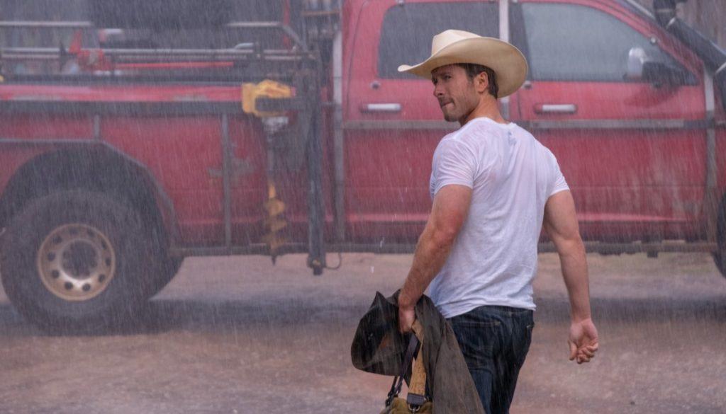 Twisters review: Glen Powell as Tyler Owens walking through the rain in a white t-shirt in Twisters