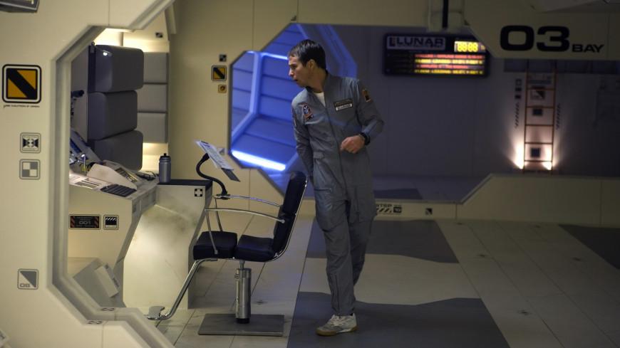 Sam Rockwell as Sam Bell, wearing a space suit and walking through a space ship