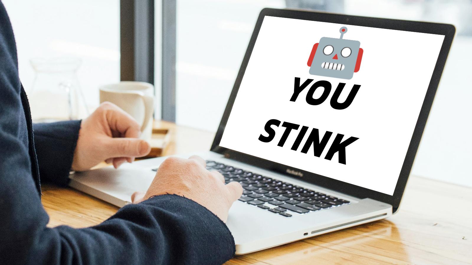 Man using a laptop with a robot emoji and the text you stink