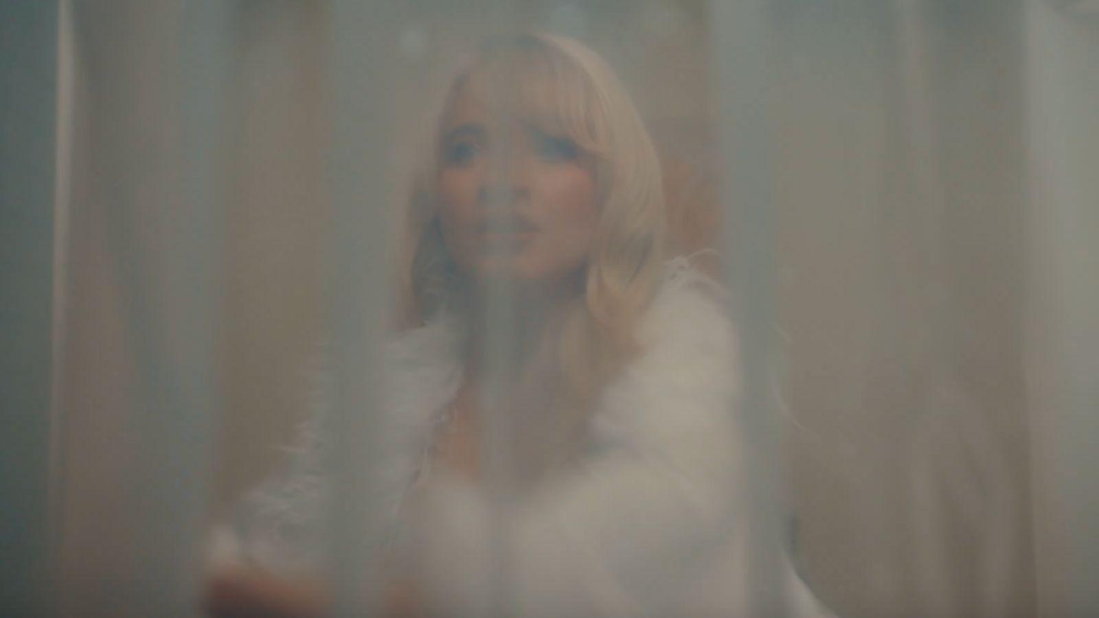 Sabrina Carpenter behind a shower curtain in the Taste music video