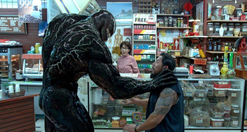 Venom movies in order: Venom holding a man by the throat in a shop